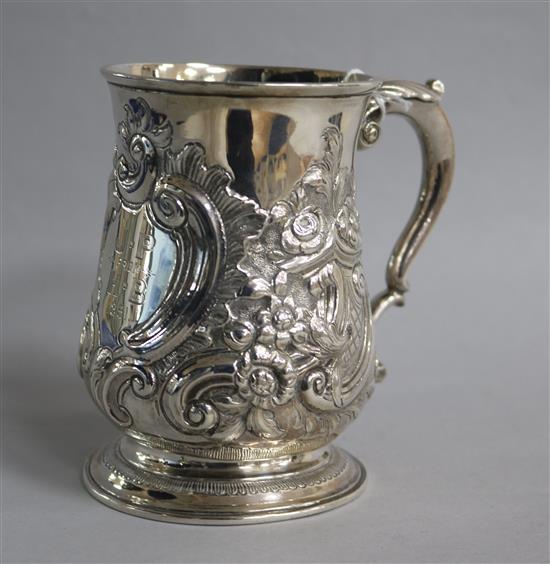 A late George II silver baluster mug with late embossed decoration and engraved inscription,